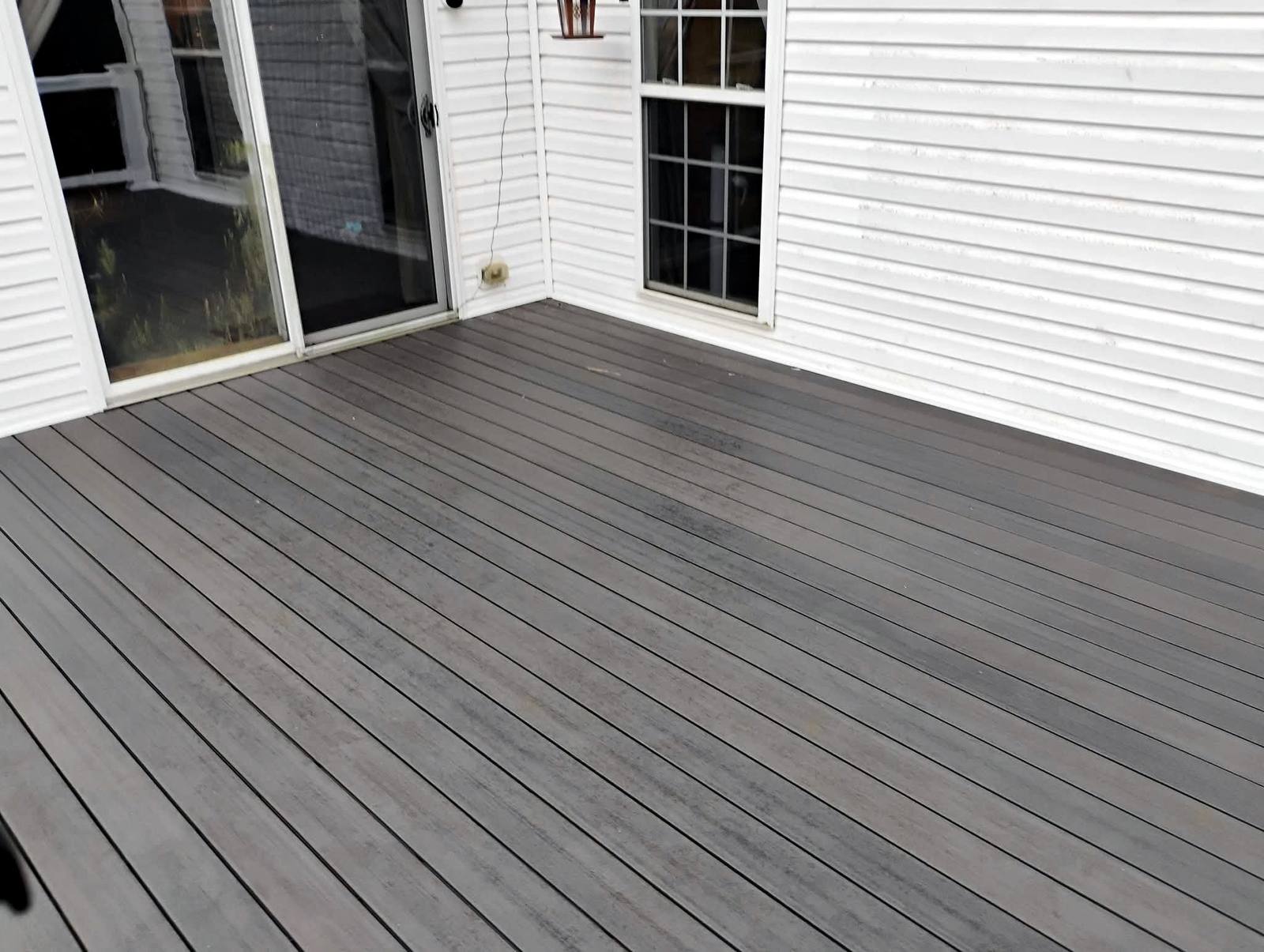 Wide gray composite deck beside a white home