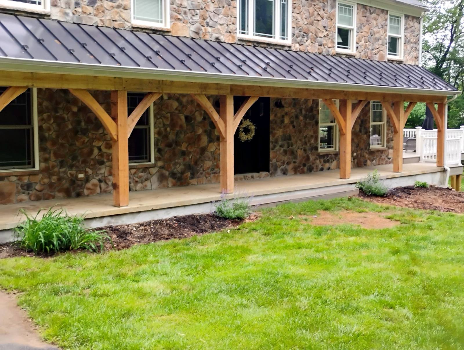 Timber-frame porch spanning a stone home