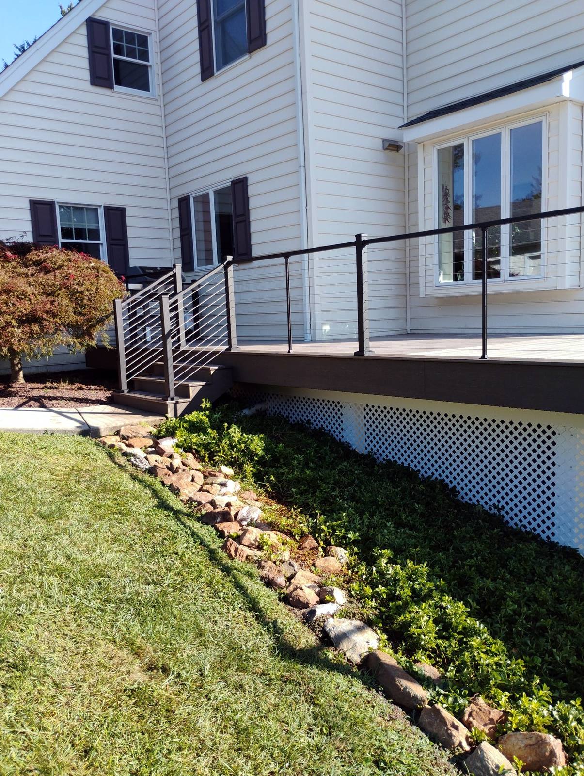 Finished exterior and deck foundation beside a landscaped bed