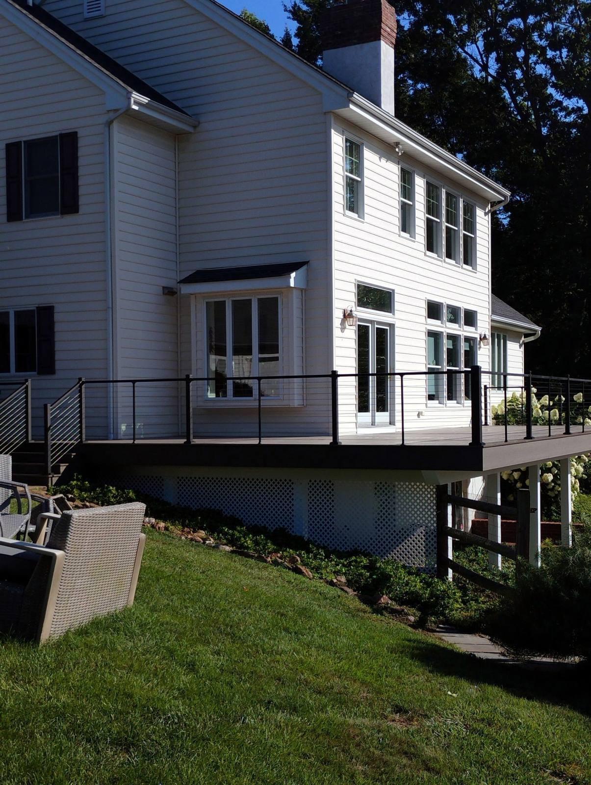 Finished elevated deck with black cable railing on a white home