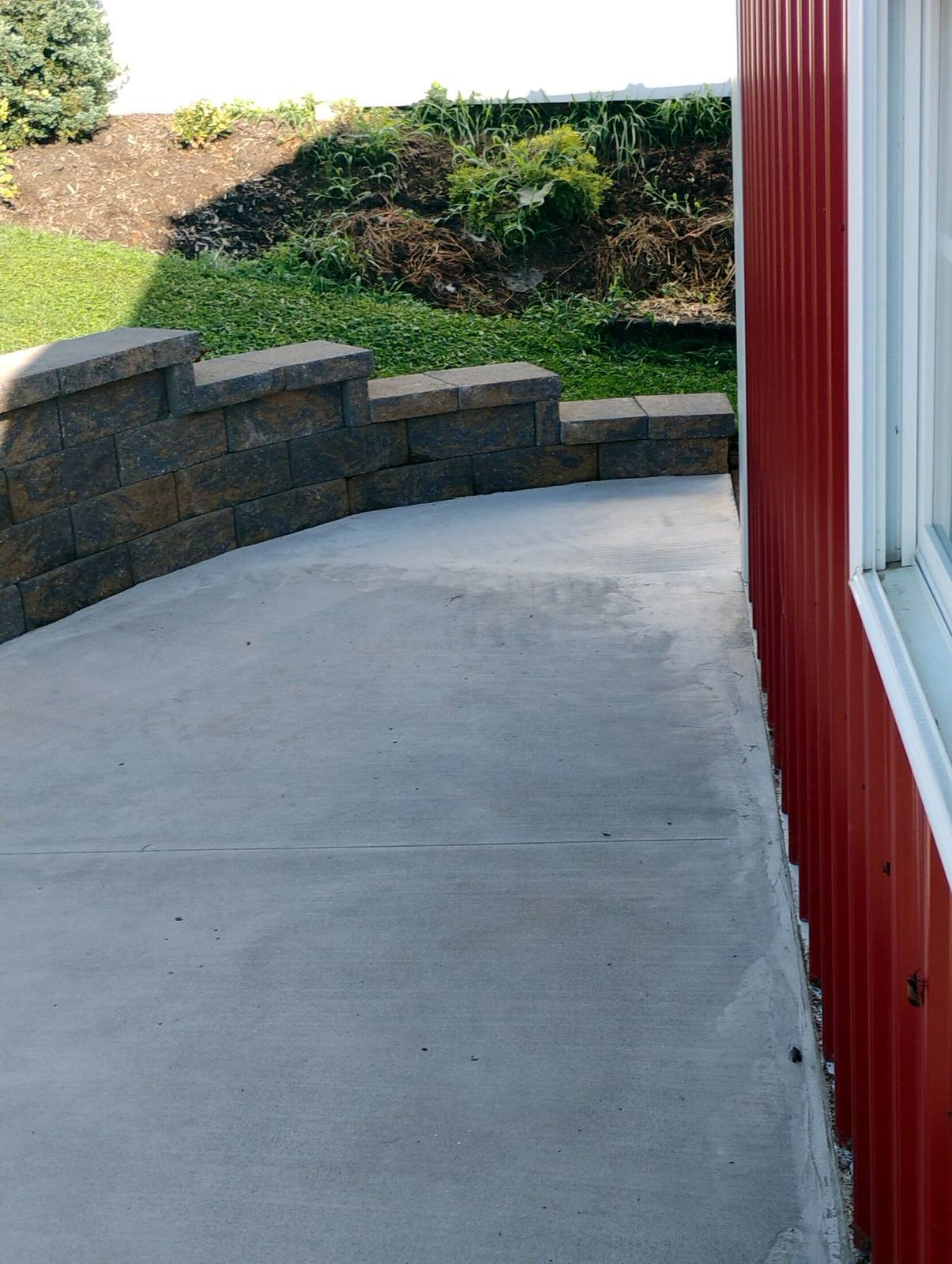 Completed concrete pad beside a red outbuilding