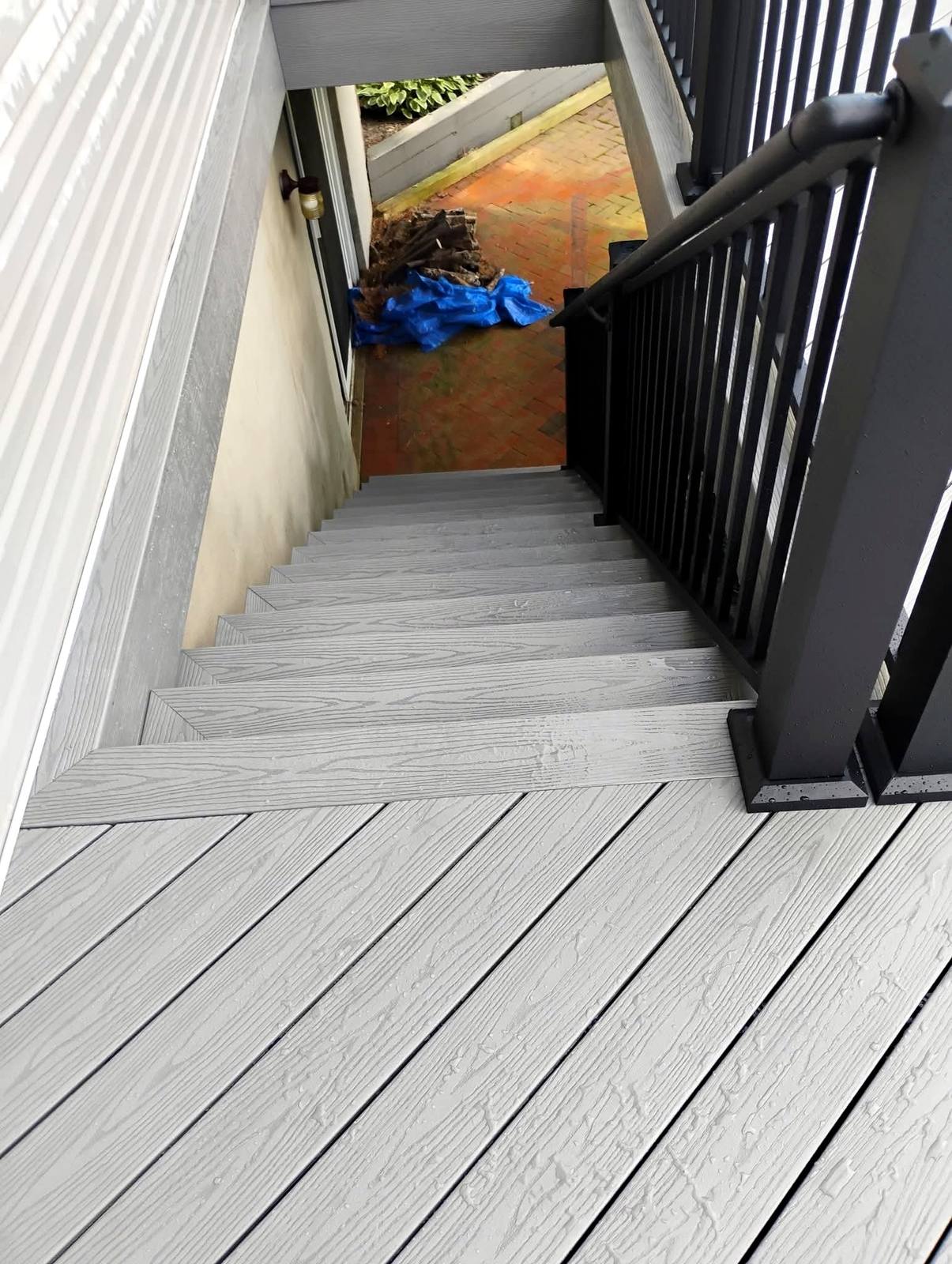 Finished gray composite stairs beside white siding